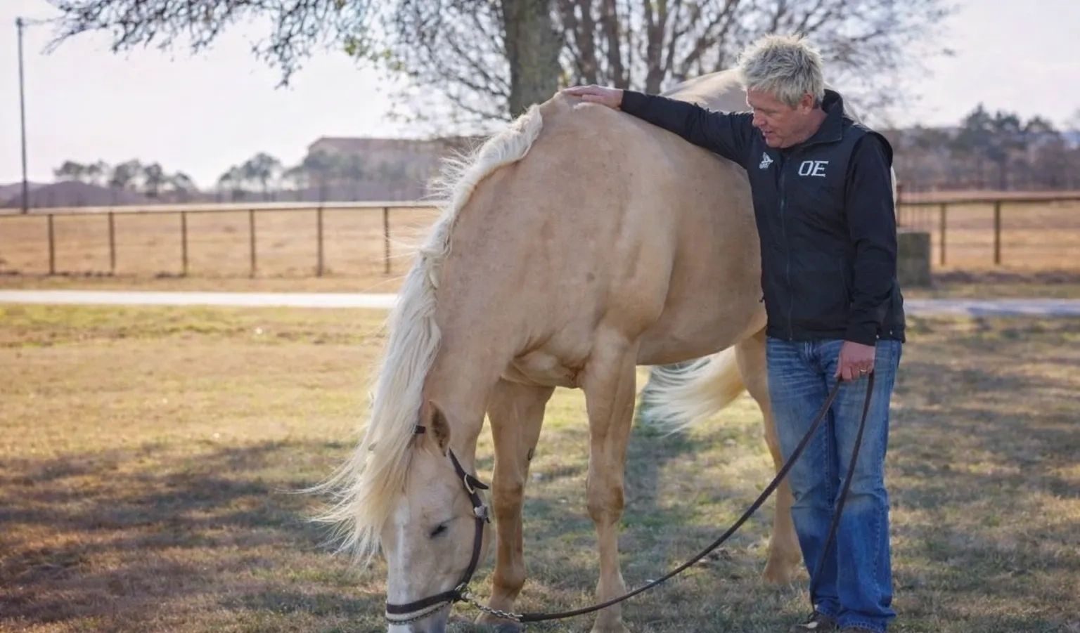 Paul Humphrey with his hand on a grazing palomino