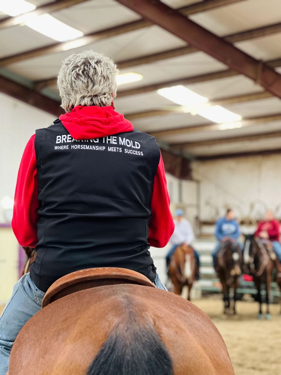 A rider in a Breaking the Mold vest watching the group from the saddle